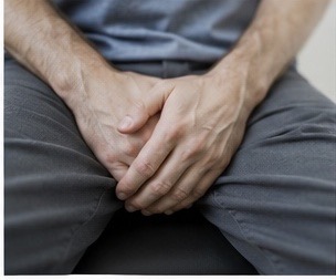 Man holding pelvic area with discomfort