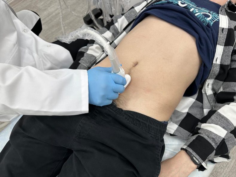 Doctor performing an abdominal ultrasound exam as part of prostate and urinary symptom evaluation